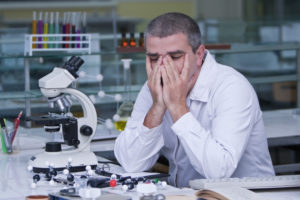 Young exhausted researcher in laboratory after a request for additional experiments.