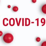 The words COVID-19 surrounded by virus-like particles.