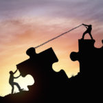 Silhouette of two people pulling giant-size jigsaw puzzle pieces together with chains, to visualise the concept of people working together to end the reign of the journal impact factor