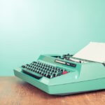 Retro old typewriter with paper on wooden table front mint green background, such as could be used to write an introduction