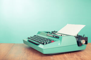 Retro old typewriter with paper on wooden table front mint green background, such as could be used to write an introduction