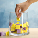 Woman taking paper piece from glass vase on table. Lottery