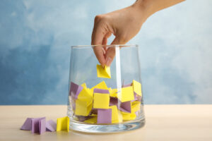 Woman taking paper piece from glass vase on table. Lottery